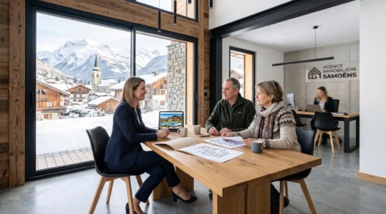 Conseillère immobilière en rendez-vous avec un couple de clients dans une agence à Samoëns, avec vue sur le village montagnard et les massifs enneigés par la vitrine